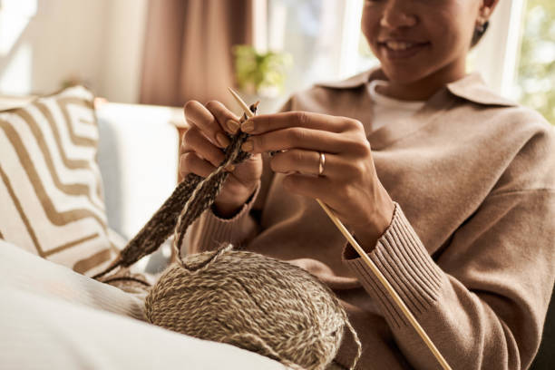 Close up of young woman knitting and enjoying cozy weekend