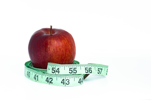 Red apple with green measuring tape on white background. Healthcare concept.