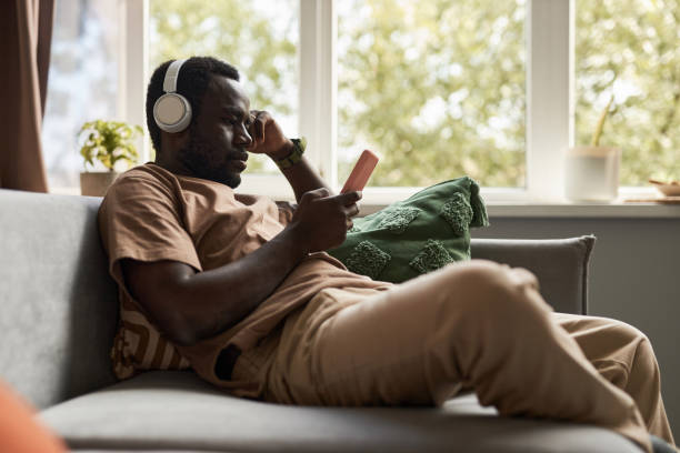 African American man using smartphone listening to music at home