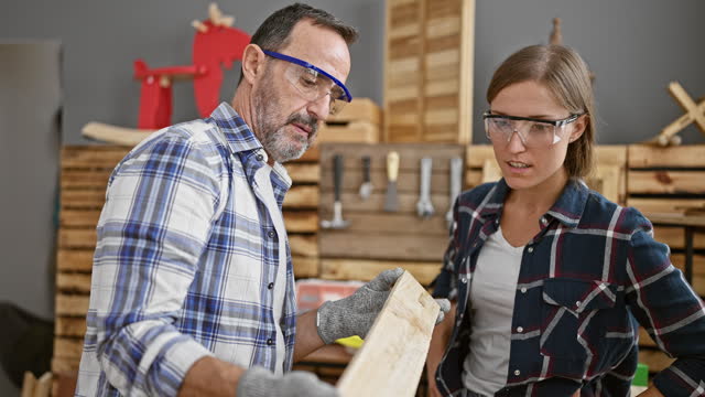 Two dedicated carpenters speak serious shop, holding lumber plank in indoor carpentry business