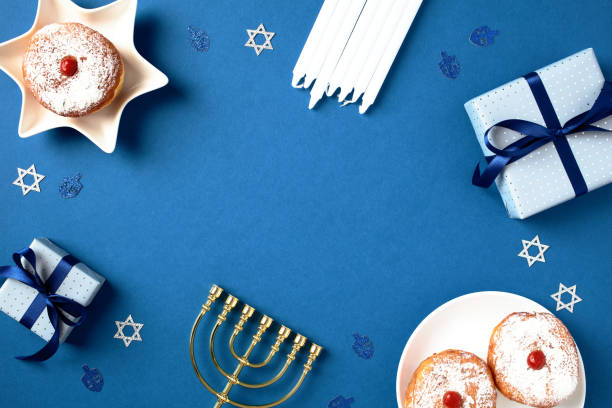 istock Hanukkah card design with traditional elements - golden menorah candlestick, gift boxes, candles, and sufganiyot. Happy holiday concept with cultural symbols 1791217424