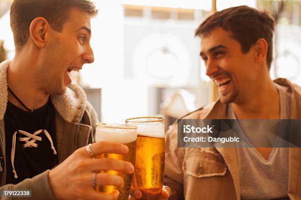Two Young Men Laughing And Drinking Beer Together Stock Photo - Download Image Now - Beer - Alcohol, Men, Celebratory Toast