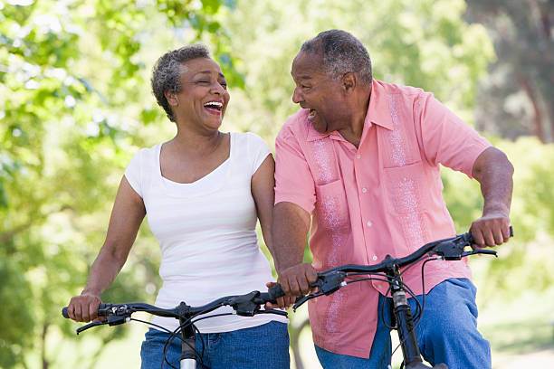 Senior couple on cycle ride Senior couple on cycle ride in countryside looking at each other laughing approaching stock pictures, royalty-free photos & images