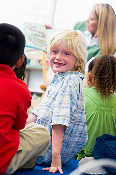 istock Kindergarten teacher reading to children, boy looking over shoulder 179123152