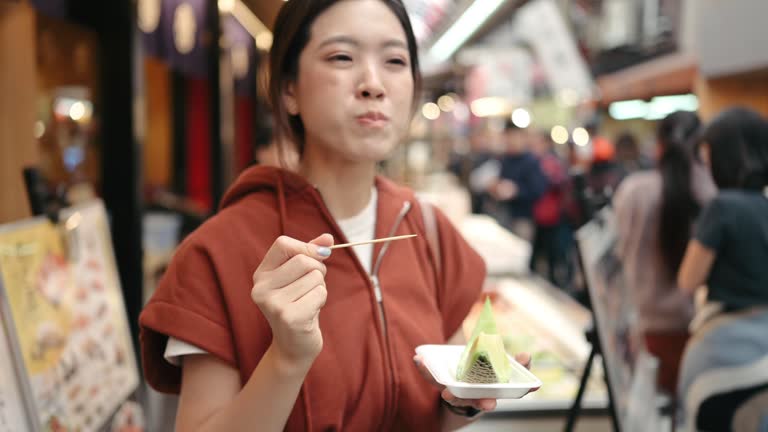 Wide angle view Asian enjoy japanese Fruit on wooden skewers n Osaka Shinsekai at Night Tsutenkaku