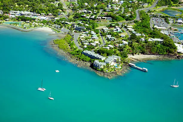 Aerial of seaside town in the Whitsundays, Queensland Australia. Looking down at a beautiful harbour, beaches and housing estate.