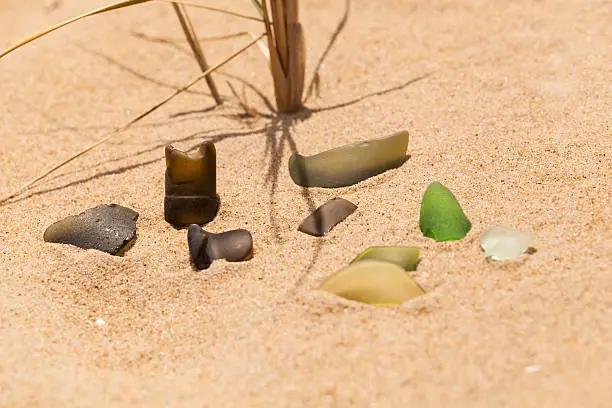 A collection of multicolored seaglass (beach glass) in the sand.