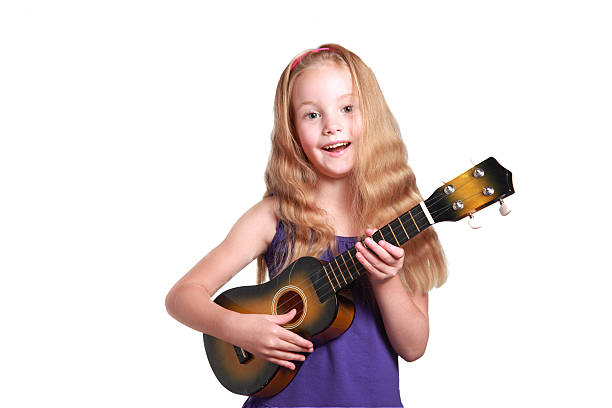 little girl playing ukulele little girl in purple dress playing the ukulele ukulele stock pictures, royalty-free photos & images