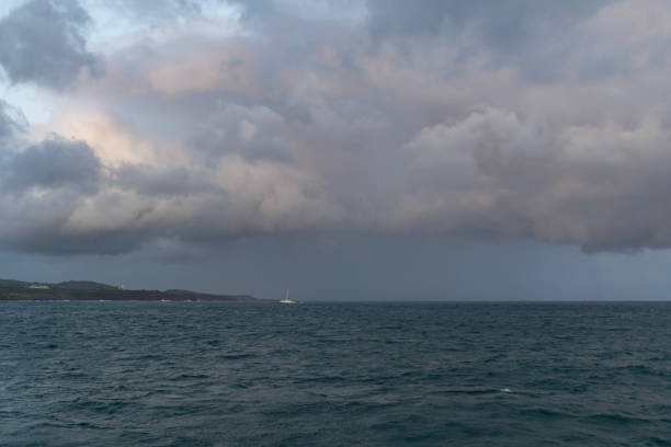 Ocean scene with rain clouds above and a boat on the water in the Pacific Ocean off of Kauai, Hawaii, United States.