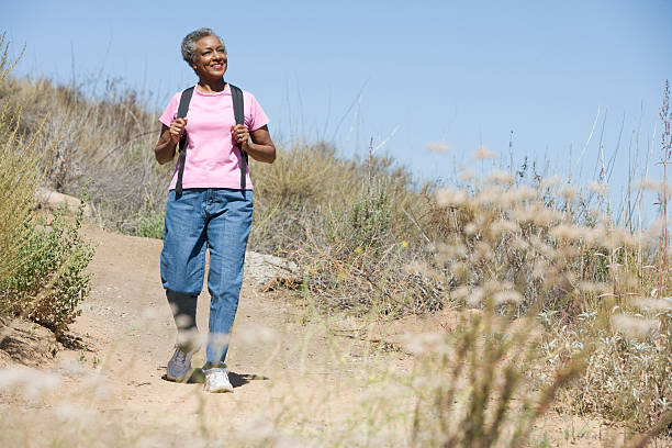 donna senior sulla passeggiata - hiking senior adult exercising outdoors foto e immagini stock