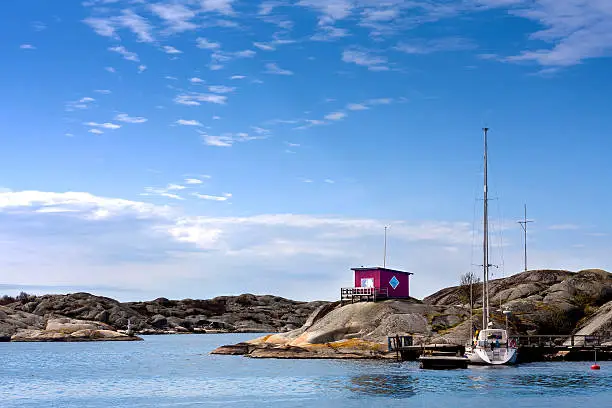 Sailingboat docked at small island with a red cottage in sweden