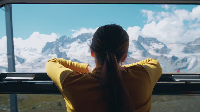 Woman looking out of the window on the train taking view on Swiss Alps Mountain