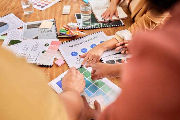 istock Hands, documents and marketing with a designer team working on a creative project together in the office. Meeting, data and strategy with a group of design people at work in the boardroom closeup 1791262754