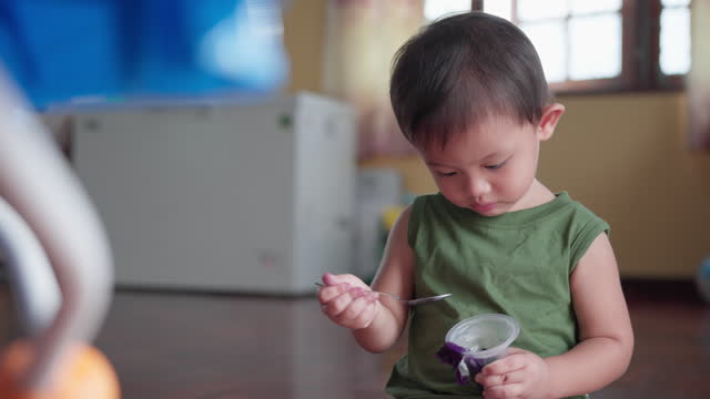 Asian baby boy eating sweet fruit jelly gelatin dessert