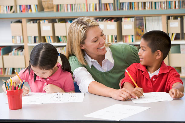 istock Kindergarten teacher helping students with writing skills 179127656