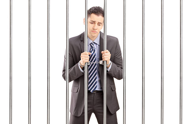 istock Handcuffed businessman in jail and holding bars 179129110