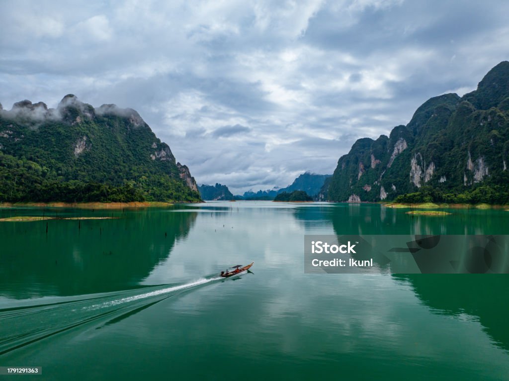 Aerial drone view of tourist boat on the lake of tropical Mountain peak , Khao Sok National Park, Thailand Above Stock Photo