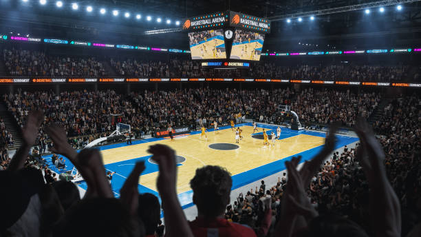 High Angle Establishing Wide Shot of a Whole Arena of Spectators Watching a Basketball Championship Game. Teams Play, Crowds of Fans Raise Hands and Cheer. Sports Channel Live Television Broadcast Ángulo alto que establece un plano amplio de toda una arena de espectadores viendo un partido del campeonato de baloncesto. los equipos juegan, multitudes de fanáticos levantan la mano y vitorean. canal de deportes transmisión de televisión en vivo