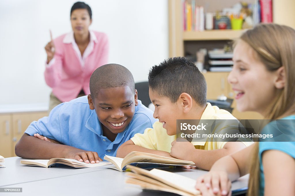 Elementary school classroom Two boys misbehaving in elementary school classroom chatting to each other Classroom Stock Photo