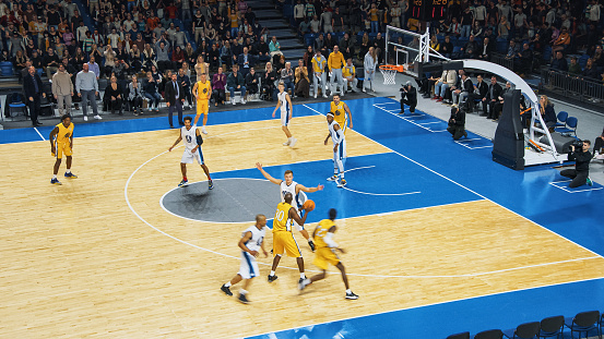 Rear view of woman aiming at basketball hoop.