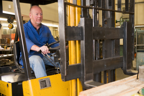 Warehouse worker in forklift sitting down
