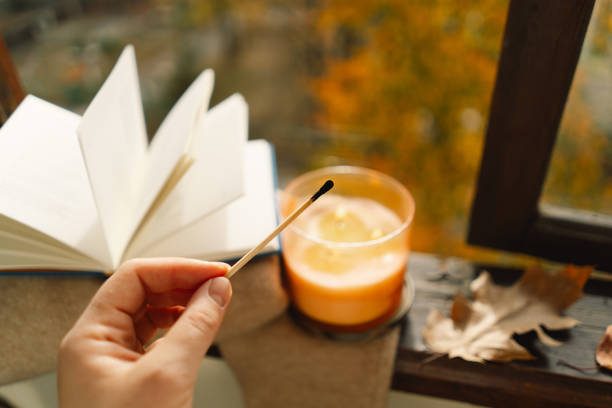 istock Hand with burning match lighting a candle on the windowsill 1791327586