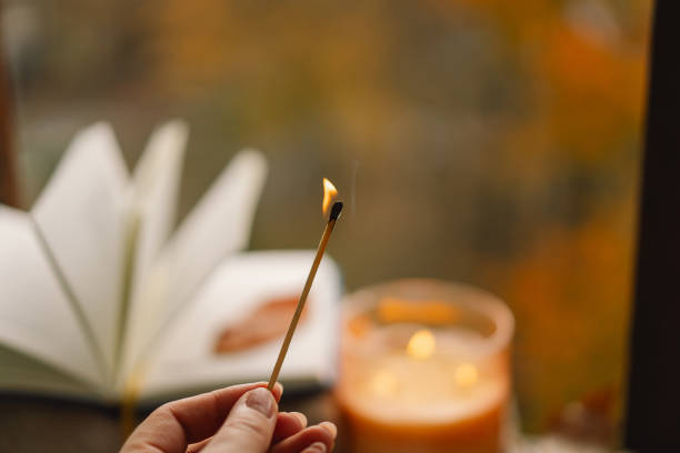 istock Hand with burning match lighting a candle on the windowsill 1791327612