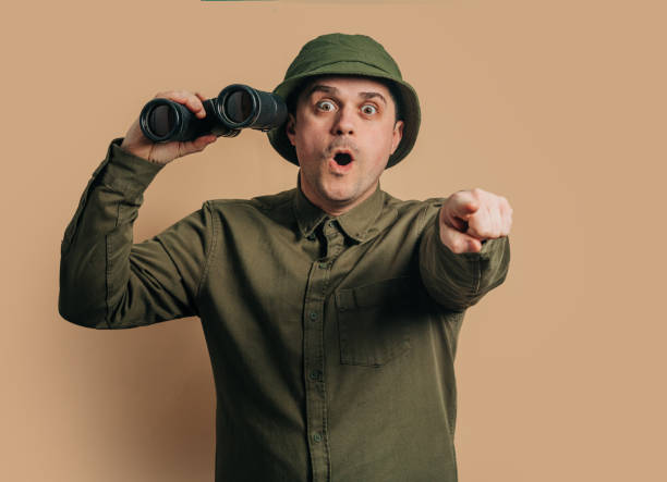 istock Stylish guy in boonie hat with binoculars on brown background 1791328716