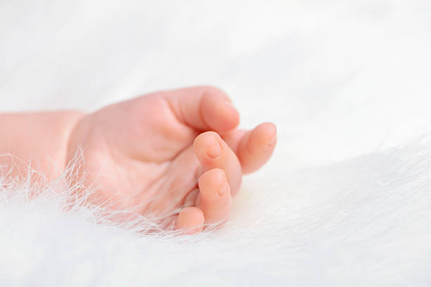 A new mum holds the hand of her baby boy when he is one day old
