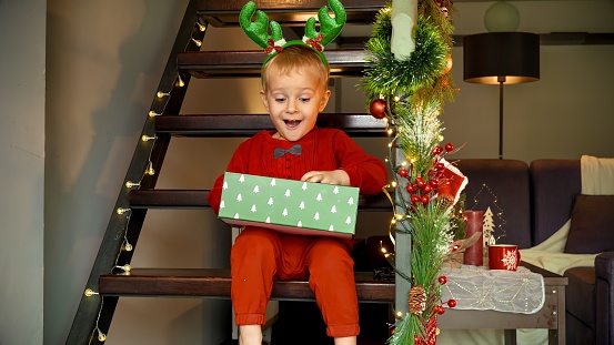 Funny little boy got excited after receiving Christmas present in gift box