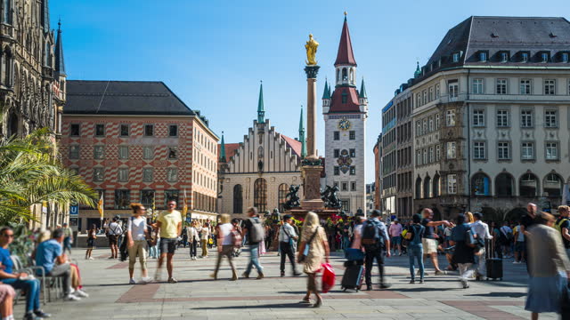 Time lapse of Crowd of People tourist walking and sightseeing attraction at Marienplatz a central square in the city centre of Munich and Mary's Column and Toy Museum in Munich, Germany in summer