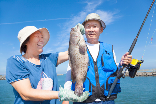 asian senior couple fishing and showing big grouper