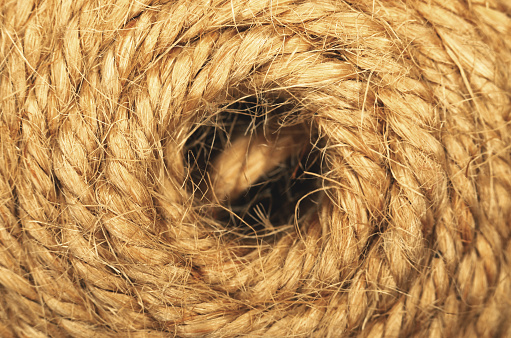 Close up of a coil of brown rope with a hole in it