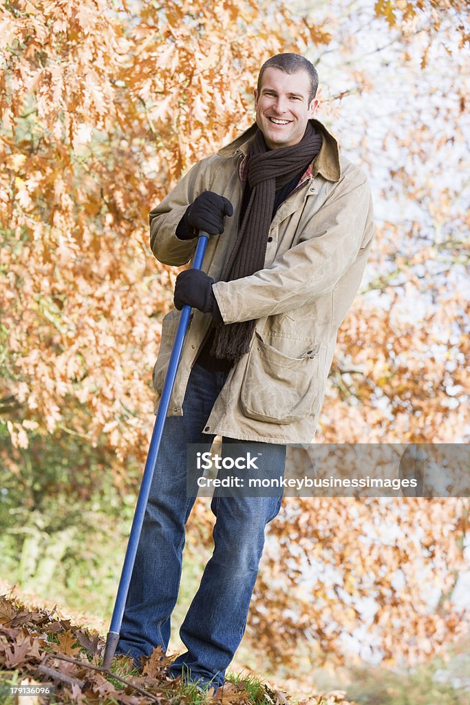 Uomo di riordino foglie d'autunno - Foto stock royalty-free di Abbigliamento