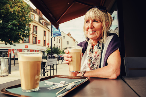 Woman sitting outdoors with a milky americano at a cafe in Evreux, France.