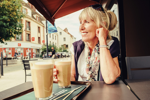 Woman sitting outdoors with a milky americano at a cafe in Evreux, France.