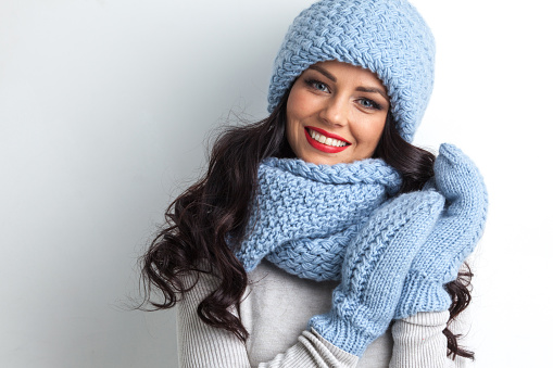 Beautiful woman in warm hat, mittens and scarf on white background