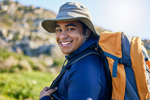 Portrait, hiker or happy man in nature walking on outdoor adventure for camping on holiday vacation. Wellness, smile or confident traveler with backpack on trekking or hiking break or journey trip