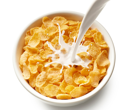 pouring milk into bowl of corn flakes, top view