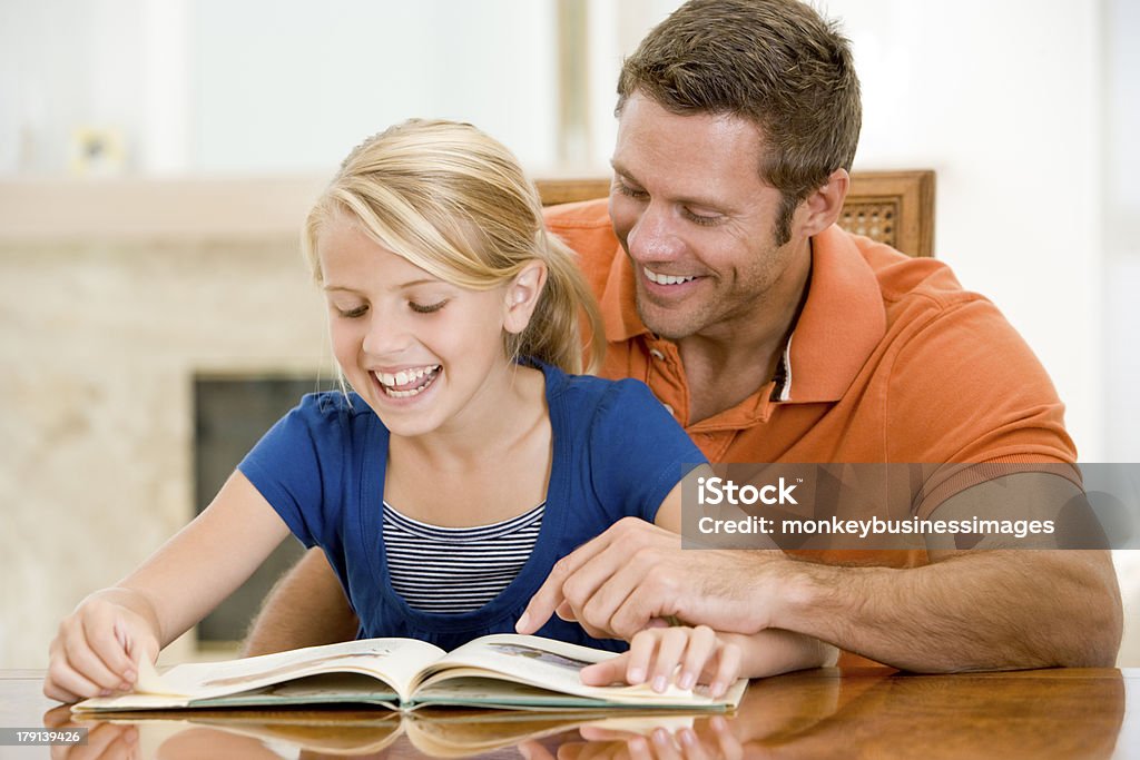 Man and young girl reading book in dining room Man and young girl reading book in dining room smiling 40-49 Years Stock Photo