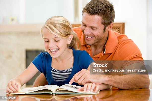 Man And Young Girl Reading Book In Dining Room Stock Photo - Download Image Now - 40-49 Years, Adult, Affectionate