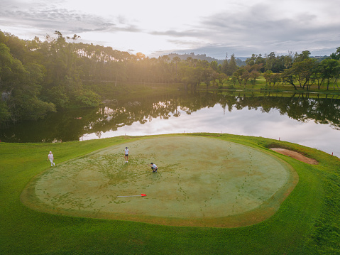 asian friends social golfers putting green weekend morning