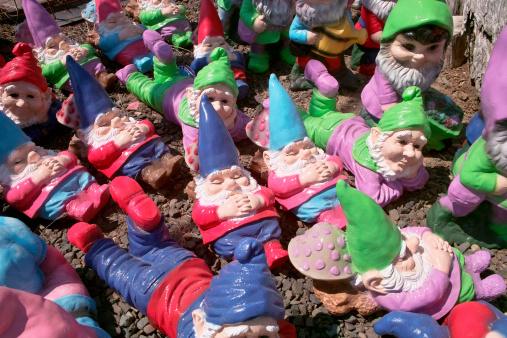A group of small garden gnomes scattered on the ground take a number of different positions - some sleeping, some lying down, and some sitting.