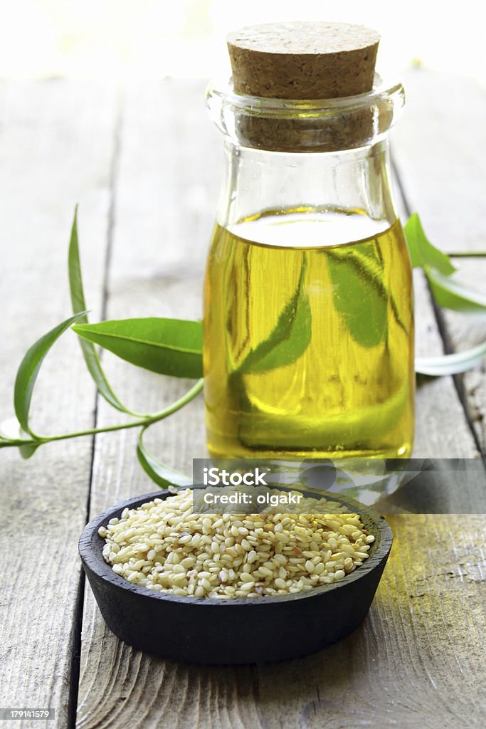 Semillas de sésamo y aceite en una mesa de madera - Foto de stock de Aceite para cocinar libre de derechos