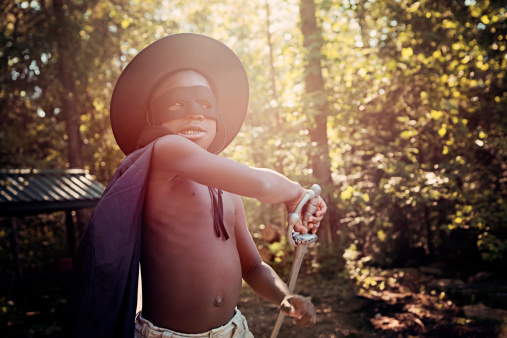Very expressive little black boy costumed playing outside. Sun flare, Copy space.