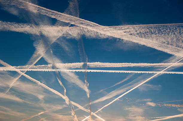 Airplane trails of condesed air in the sky Pattern of airplane trails of condensed air crisscrossing each other against the blue sky parallel photos stock pictures, royalty-free photos & images