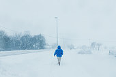 Woman in Blue Coat Admiring Winter Walking on Street in Scandinavian Village During Heavy Snowfall