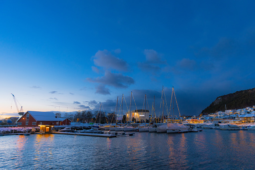 Majestic winter night over the boats in Christmas lights in the authentic Scandinavian town Ulsteinvik during twilight