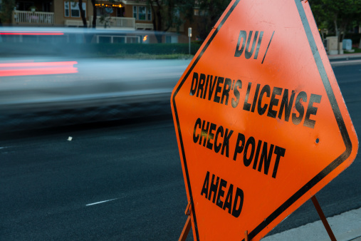 DUI (sobriety) / Driver's License Checkpoint Ahead sign on side of roadway with cars in motion in background approaching checkpoint