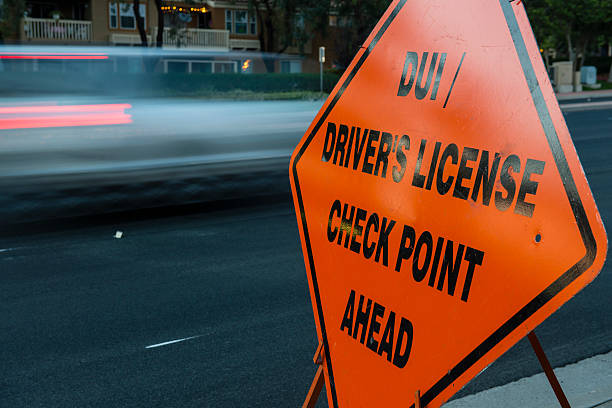 DUI and Driver License Checkpoint motion DUI (sobriety) / Driver's License Checkpoint Ahead sign on side of roadway with cars in motion in background approaching checkpoint security barrier photos stock pictures, royalty-free photos & images
